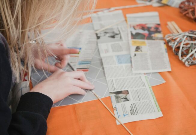 Dziewczyna skręca gazetę na wiklinę papierową